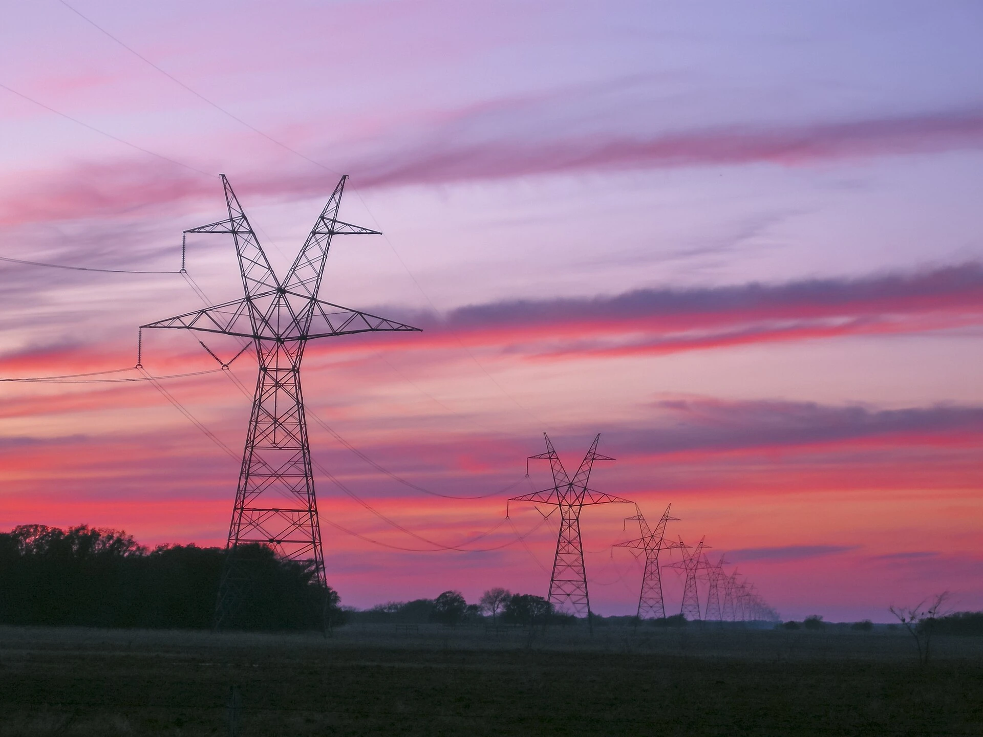 Real photograph of high-voltage transmission towers and lines at sunset in East Texas.